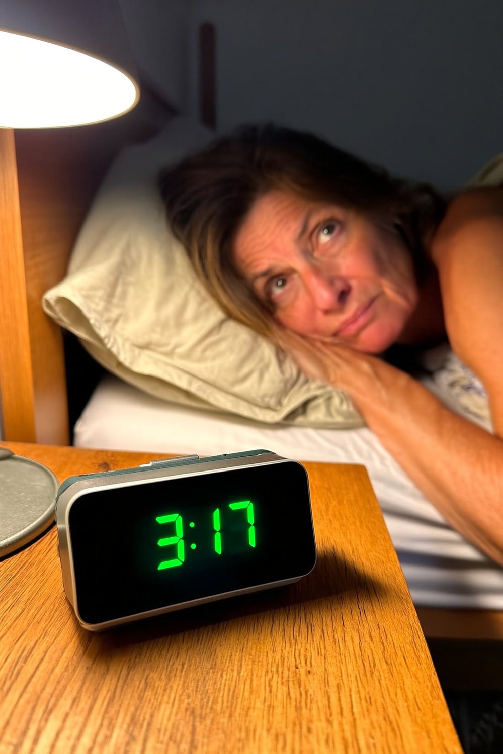 Mujer despierta de noche, reloj marcando las 3:17